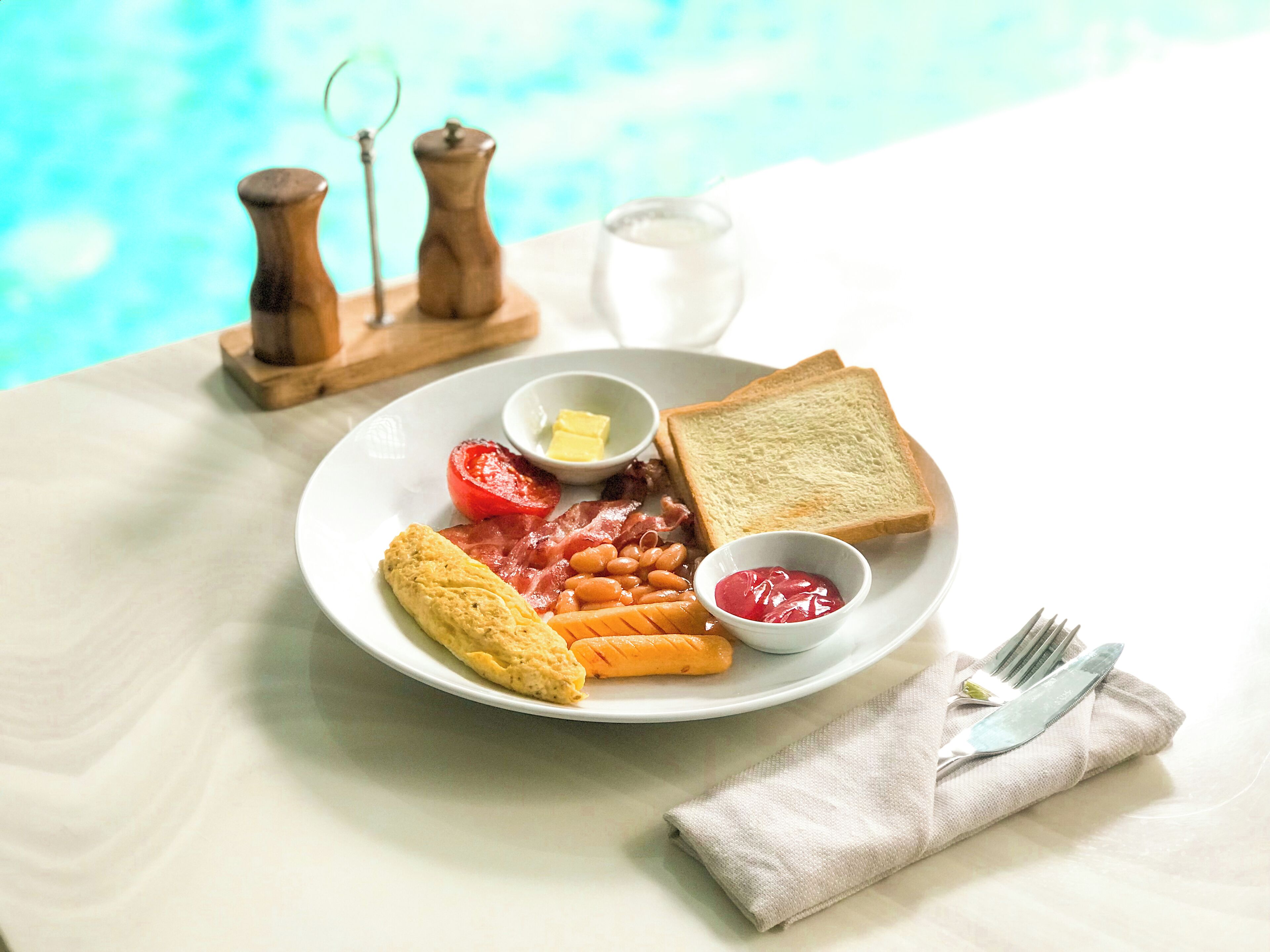 A plate with toast, eggs, bacon, tomatoes, beans, and ketchup.