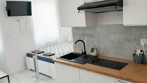 A modern kitchen with white cabinetry, a black sink, and a stainless steel range hood. - Souvenirappart Sienkiewicza 3B (Bydgoszcz)