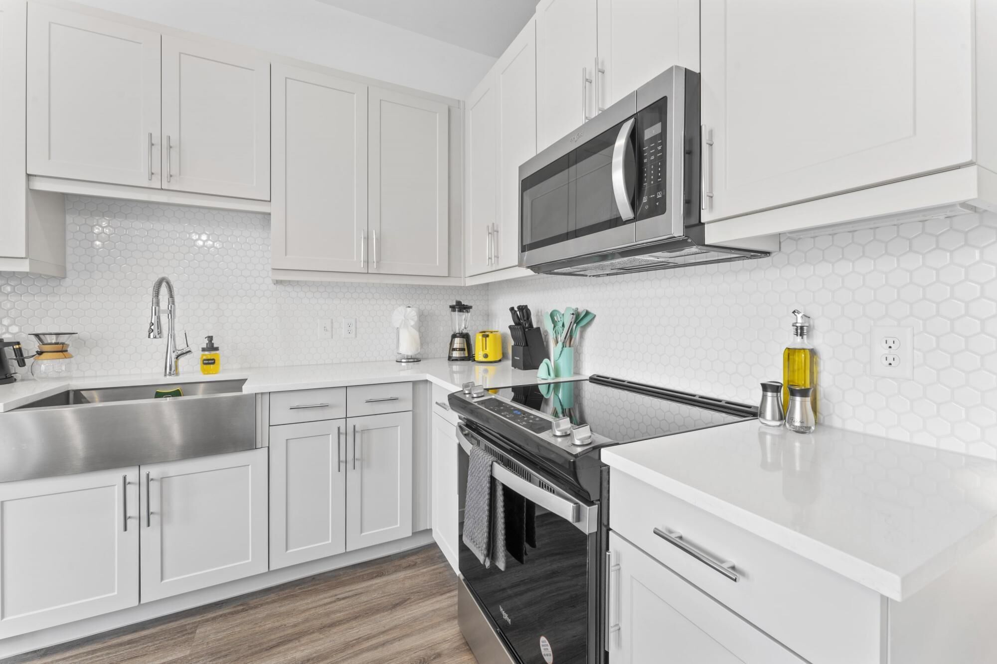 A modern kitchen with white cabinetry, a stainless steel sink, a microwave, and a built-in oven.