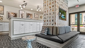 A reception area with a sofa, a small round table, a wall-mounted TV, and a patterned wall. - Central Hyde Park Studio Close to UT Moody Center (Austin)