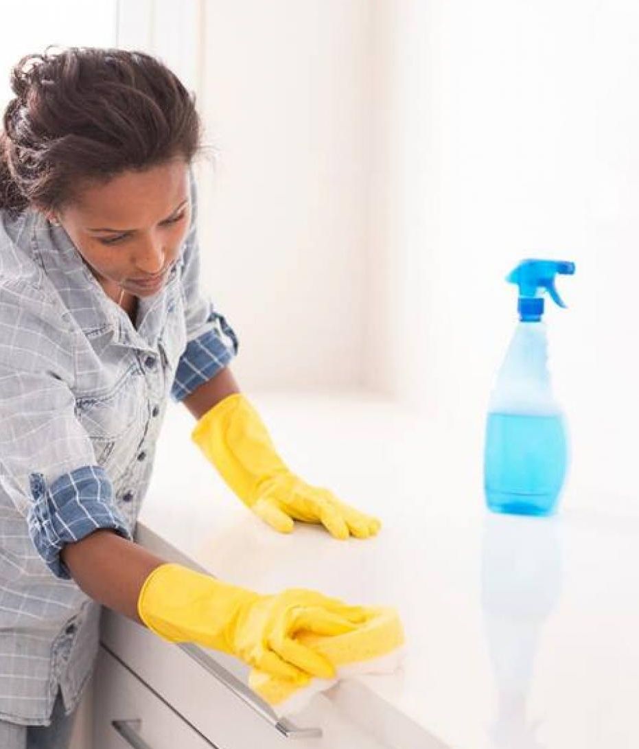 A person cleaning a surface with a spray bottle.