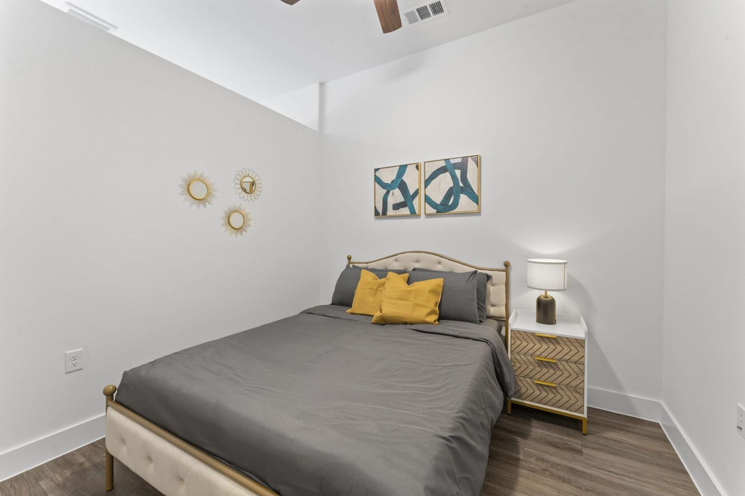 Un dormitorio con cama, mesita de noche, lámpara y decoración en la pared.