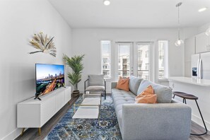 Una sala de estar moderna con un televisor de pantalla plana, un sofá, una mesa de centro y una planta en maceta.