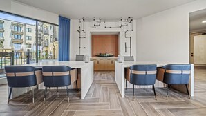 A modern kitchen with a central island, wooden cabinets, and a view of the city through large windows. - Boho Soco 1BR Queen Suite w Gympickleballlaundry (Austin)