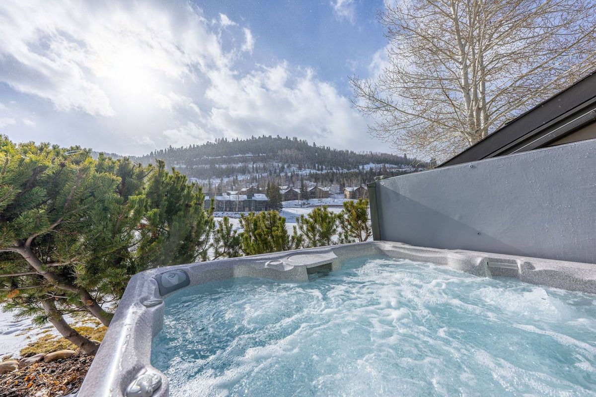 A hot tub with a view of a snowy landscape and trees.