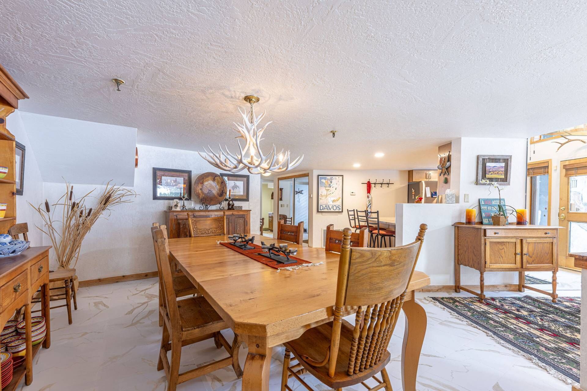Un comedor amplio con una gran mesa de madera, varias sillas y una lámpara decorativa.