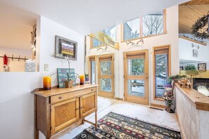 Ein modernes Interieur mit einem Holzkabinett, einem gemusterten Teppich und einem großen Fenster mit Blick auf Bäume.
