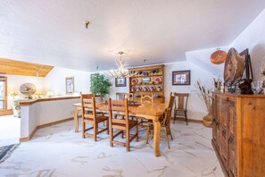 Ein Essbereich mit Holztisch und Stühlen, einer Kandelaber und einer Vitrine mit Dekoration.