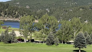 Un campo de golf con un lago, árboles y una montaña al fondo.