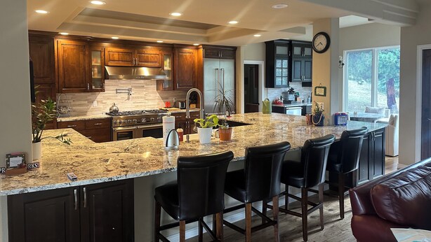 Una cocina moderna con armarios de madera oscura, encimera de granito y una isla integrada con taburetes de bar.