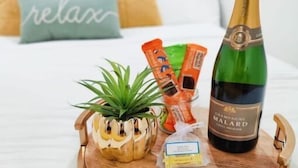 A bed with a tray holding a bottle of champagne, snacks, and a small plant. - Unique, Modern and Lovely Space! (East Providence)