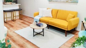 A modern living room with a yellow sofa, a round coffee table, and a wooden ceiling. - Unique, Modern and Lovely Space! (East Providence)