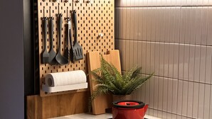 A kitchen with a pegboard holding utensils, a red pot on the stove, and a plant. - HHZib - homestay on a peaceful hill (Seoul)