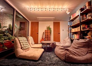 A cozy living room with a brick wall, a bookshelf, and a guitar.