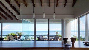Une chambre moderne avec de grandes fenêtres, un plafond en bois et une vue sur la mer.