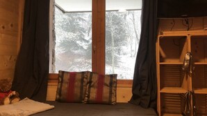 Een slaapkamer met een bed, een raam met gordijnen en een houten garderobe.