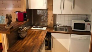 Een keuken met houten kastjes, een magnetron, een spoelbak en een fornuis.