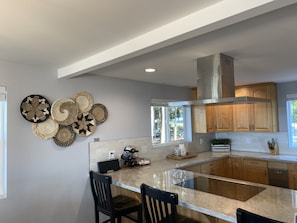 A modern kitchen with a central island, wooden cabinets, and a backsplash.