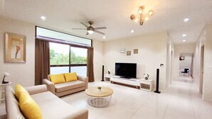 Uma sala de estar moderna com sofá, mesa de centro, televisão e ventoinha no teto.