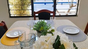 Uma mesa de jantar posta com pratos, copos, jarra e um vaso de flores.