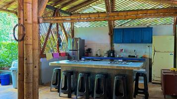 Una cocina con una isla central, taburetes y un refrigerador.