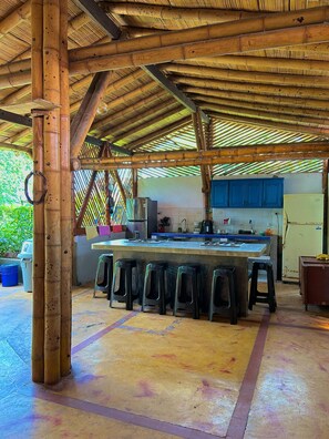 A kitchen with a central island, stools, and a refrigerator. - El Prado EcoHotel (Montenegro)