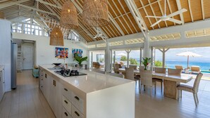 A spacious kitchen with a large island, white cabinetry, and a view of the ocean. - Casa Del Mar (Lembongan Island)