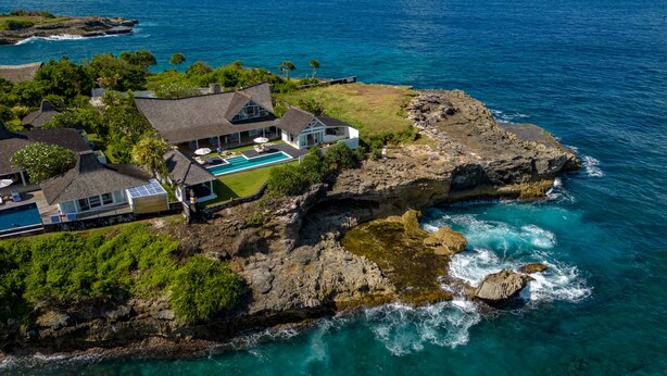 A coastal property with a large house, a swimming pool, and a rocky shoreline. - Casa Del Mar (Lembongan Island)