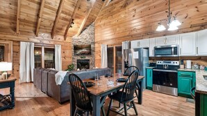 Un intérieur en bois comprenant un coin repas, une cuisine et une cheminée en pierre.