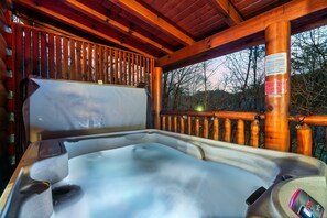 A hot tub in a wooden cabin with a wooden railing and a view of trees. - Smoky Mtn Fall Foliage Cabin – Hot Tub, Indoor Pool, Near Dollywood, Sleeps 6 (Sevierville)
