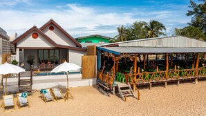 A beachside resort with a pool area, beach chairs, and a covered seating area. - Beach Front Villa with 3 Bedrooms - CA3 (Cha-am)