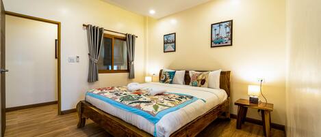 Un dormitorio con una cama de madera, una mesita de noche con una lámpara y una ventana con cortinas.