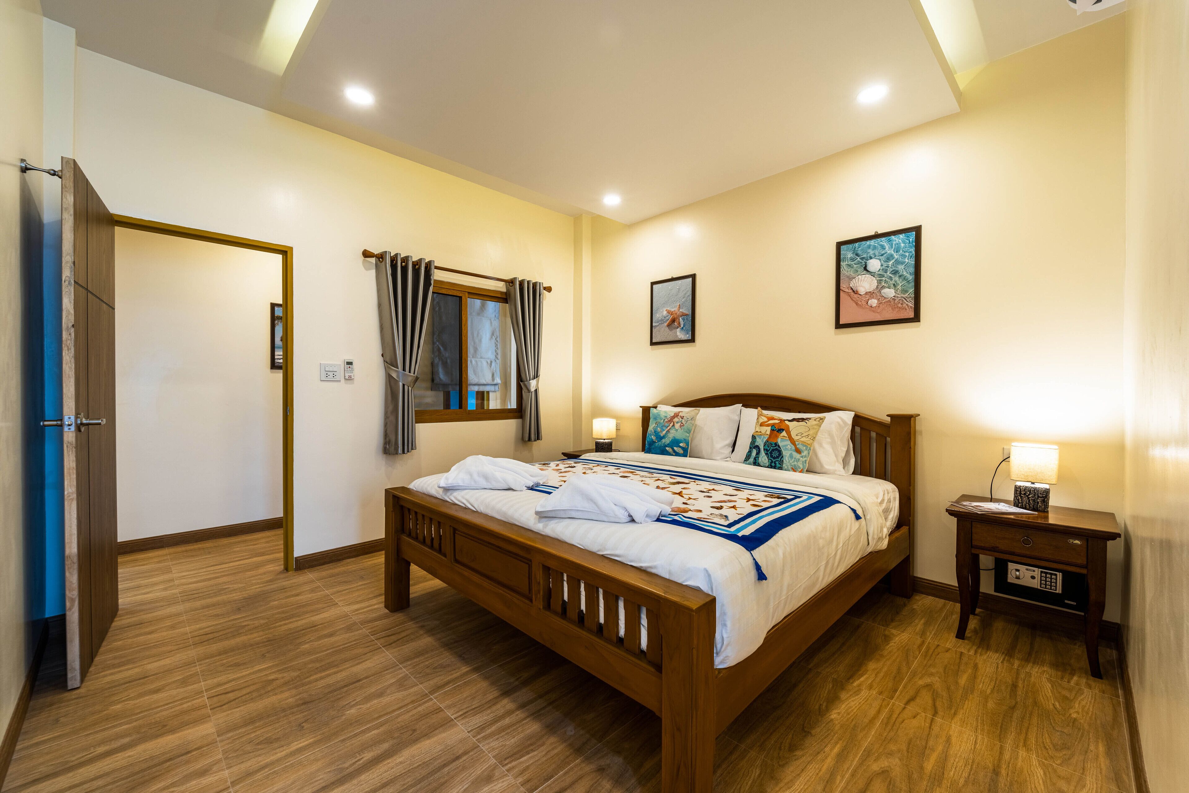 A neatly arranged bedroom with a wooden bed, a bedside table with a lamp, and a window with curtains.