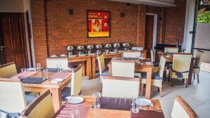 Een restaurant met bakstenen muren, houten tafels en rieten stoelen.