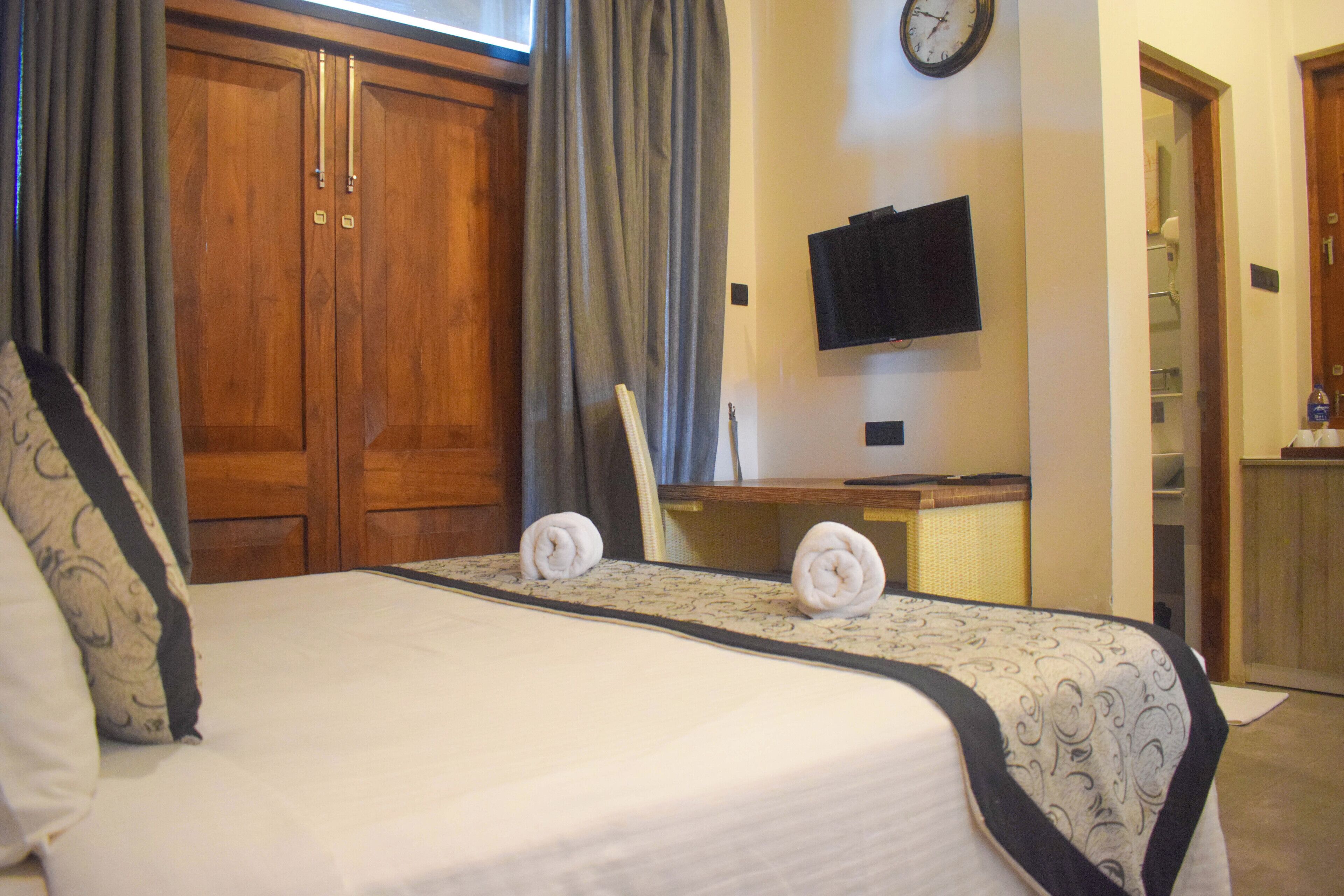 A hotel room with a bed, a desk, a television, and a wardrobe.
