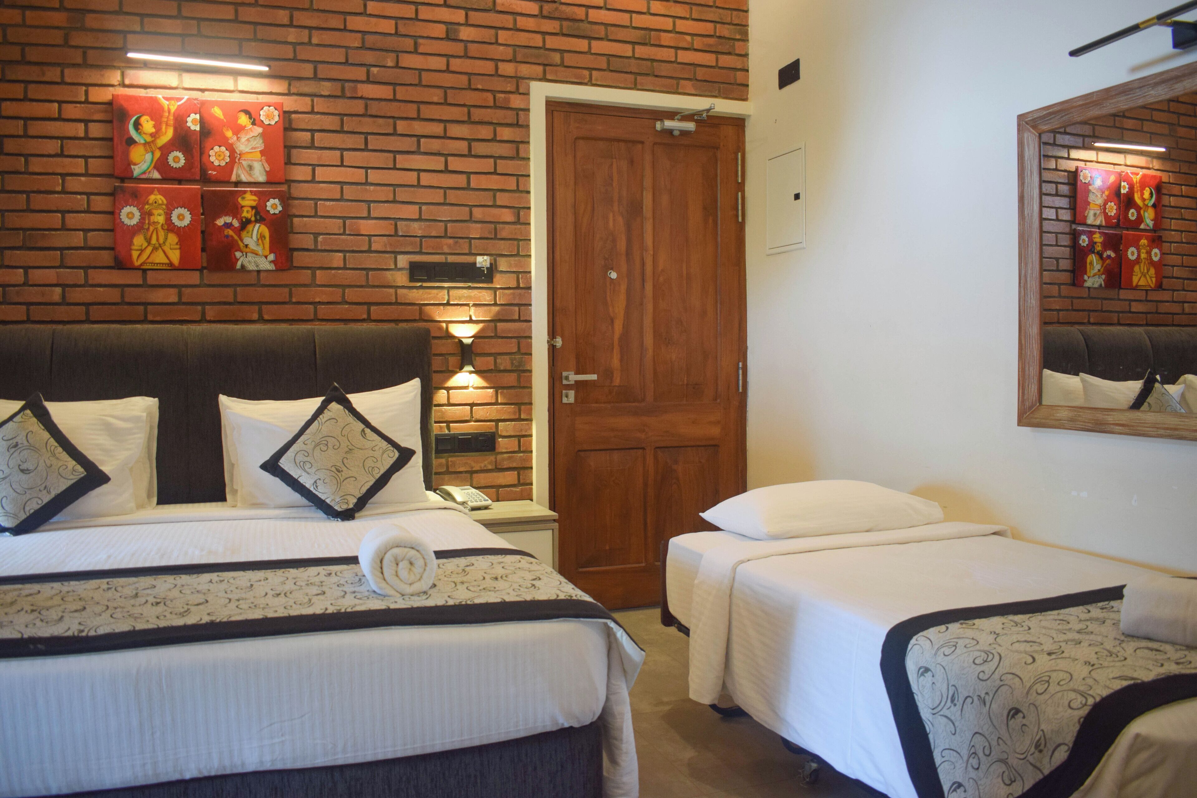 A hotel room with two beds, a brick wall, and artwork.