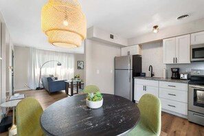 Una cocina moderna con gabinetes blancos, un refrigerador de acero inoxidable y un microondas.
