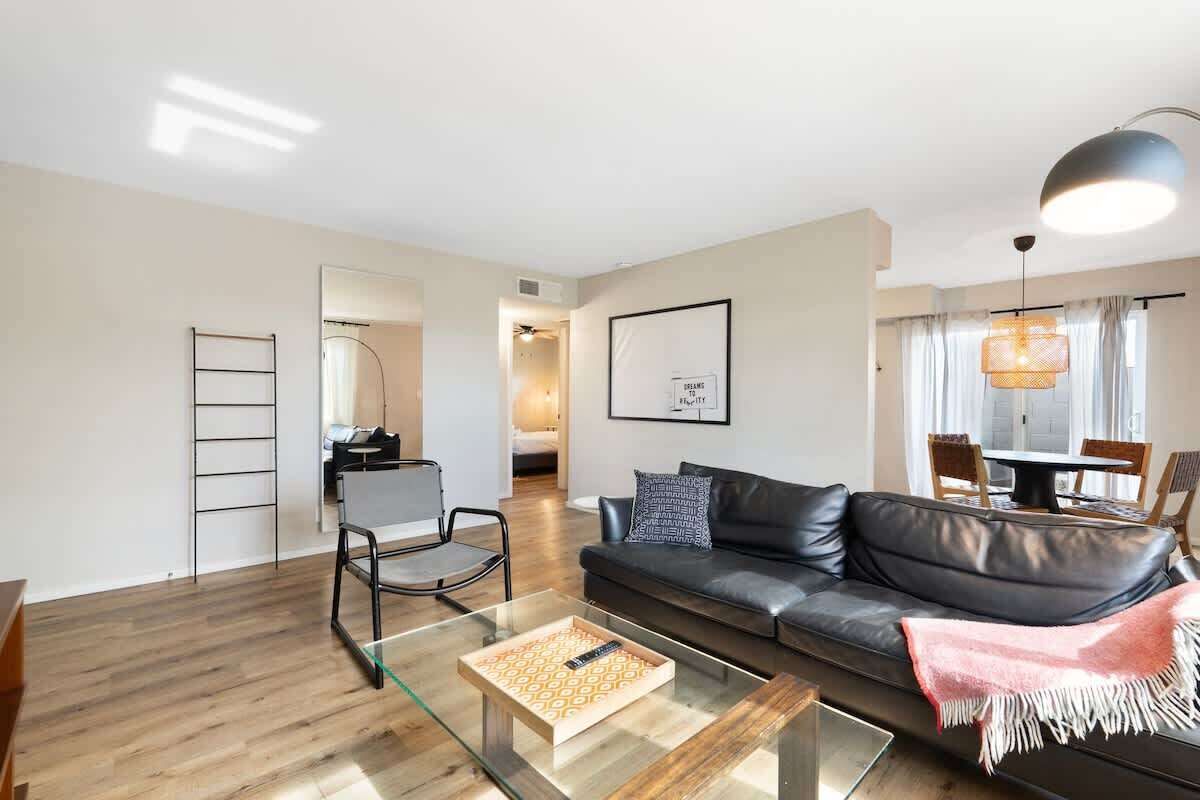 A modern living room with a leather sofa, a glass coffee table, and a dining area with a table and chairs.