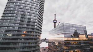A modern urban skyline with a prominent tower and reflective glass buildings.