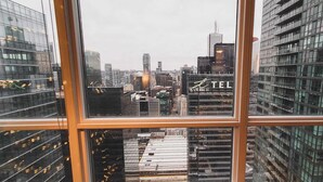 A cityscape through a window with multiple high-rise buildings, including a prominent 'TEL' sign.