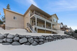 A multi-story house with a balcony, a stone retaining wall, and a clear sky.