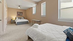 Un dormitorio con dos camas, una mesita y un ventanal.