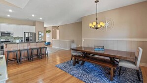 Una cocina moderna con armarios blancos, electrodomésticos de acero inoxidable y una isla central con taburetes.