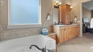 Un baño con una bañera grande, un lavabo doble y un espejo con apliques de pared.