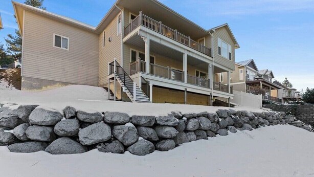 Un edificio residencial de varios pisos con un muro de contención de piedra, un balcón y una escalera que conduce a la entrada.