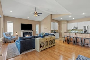 A spacious living room with a fireplace, a television, and a kitchen area with bar stools. - Spacious 6BR retreat near downtown Spokane—views, garage & fun! (Spokane)