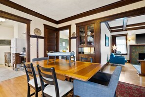 Ein Essbereich mit Holztisch und Stühlen, einem blauen Sofa und einem Schrank mit Glastüren.