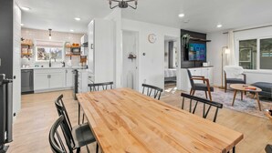 Una cocina moderna con armarios blancos, una mesa de comedor de madera y una araña.