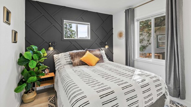 Un dormitorio moderno con cama, mesita de noche, lámpara y ventana con cortinas.