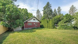 A residential property with a red house, a fenced yard, and a dense tree line. - 2BR + 1BA, Small Town Feel, Pets Allowed (Spokane)